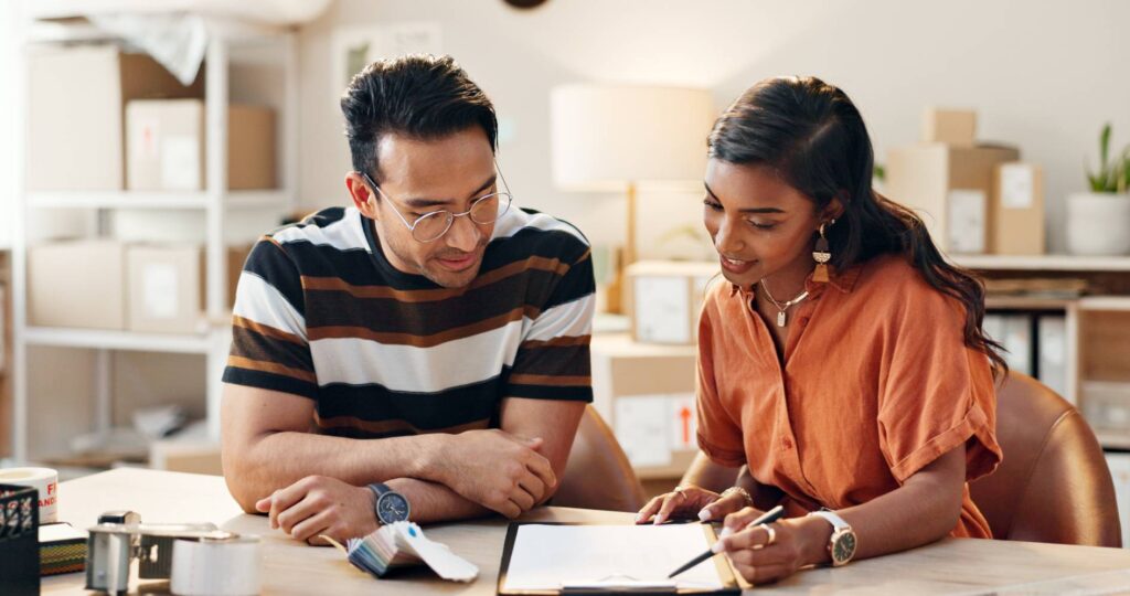 Man and woman working at a table. She is coaching him on something on a piece of paper