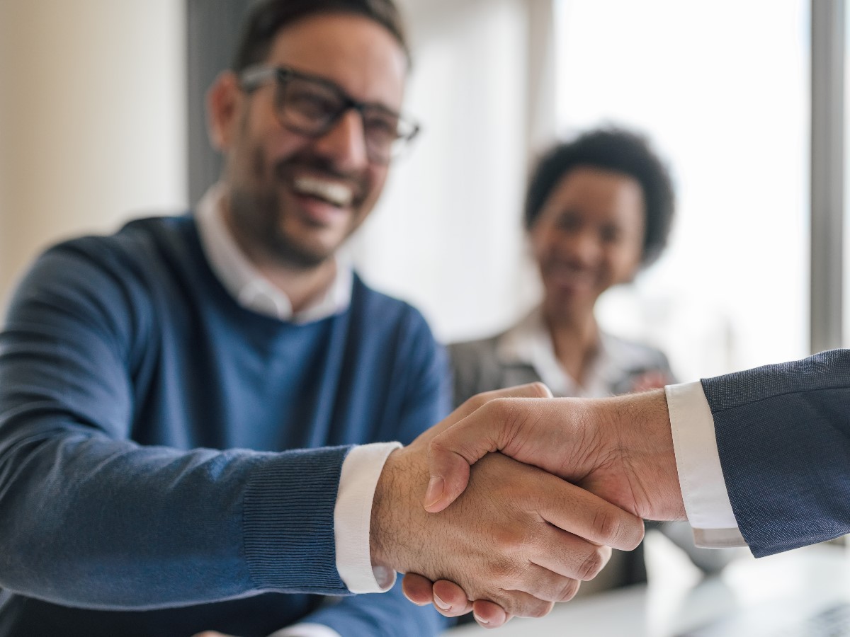 Two men shaking hands. One is smiling from ear to ear, because he has graduated from our Mars Venus Life and Relationship Coach certification.